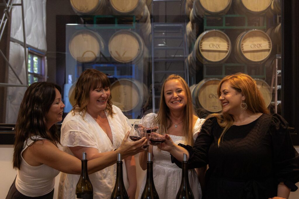 Guests raising glasses of red wine among barrels at the Cellar'd experience