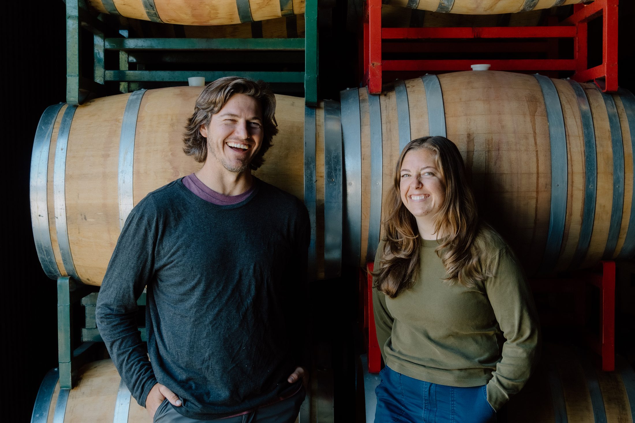 Winemaker Drew Nenow and Lauren Lange standing in front of stacked oak barrels in the ONX cellar